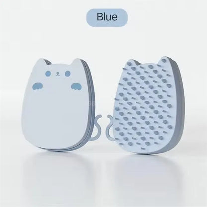 Blue silicone and sponge pet grooming brush with dual comb teeth on a wooden surface.