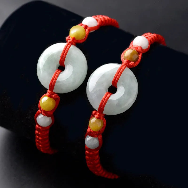 Round emerald green jade pendant on an adjustable red rope bracelet cord.