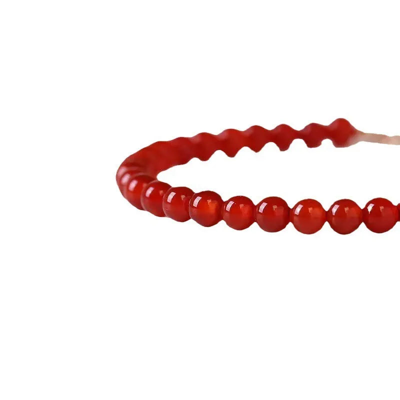 Slim red agate bead bracelet for women on a wrist, classic minimalist jewellery style.