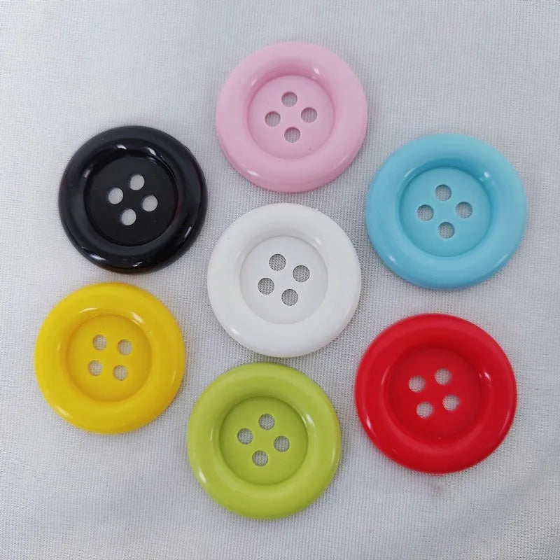 Assorted oversized round plastic buttons in various colours showing four-hole sew-through design.