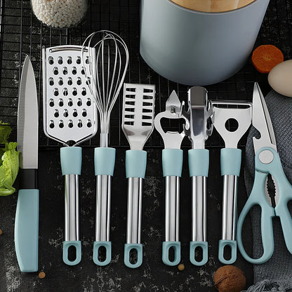 Stainless steel kitchen utensil set with whisk, grater, peeler, scissors and other tools on grey background