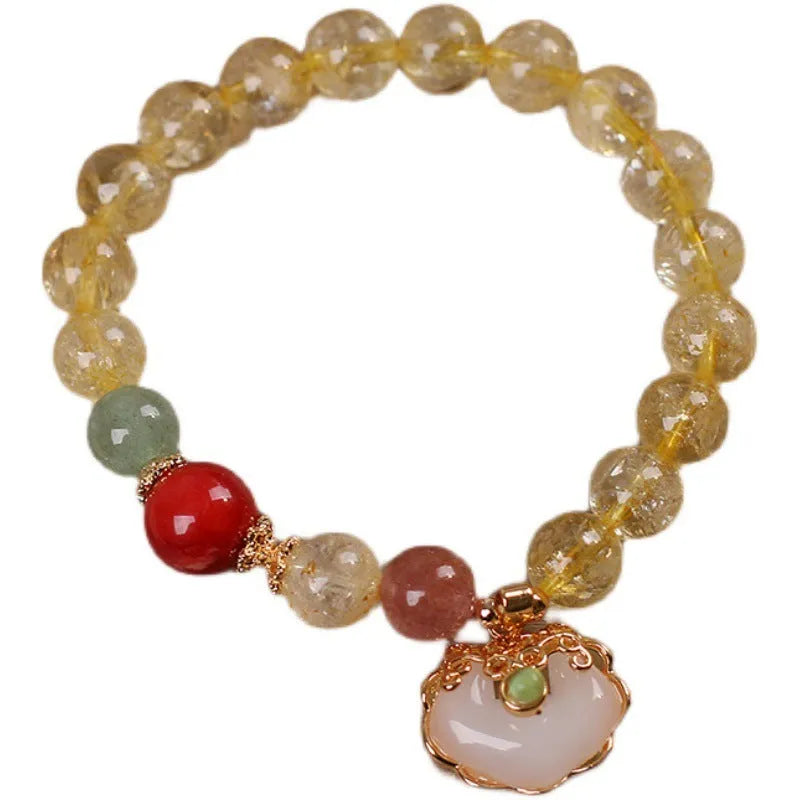 Women's yellow citrine jade ruyi pendant bracelet on wrist, alloy construction.