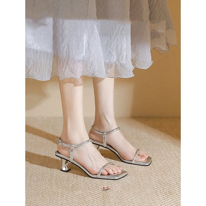 Black women's high heel sandals with a single ankle strap, square toe, and thick heel.