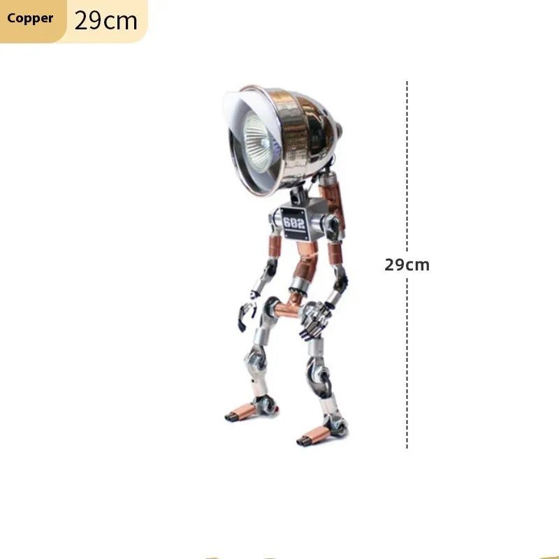 Silver metallic robot-shaped decorative desk lamp with internal LED glow on a wooden surface.