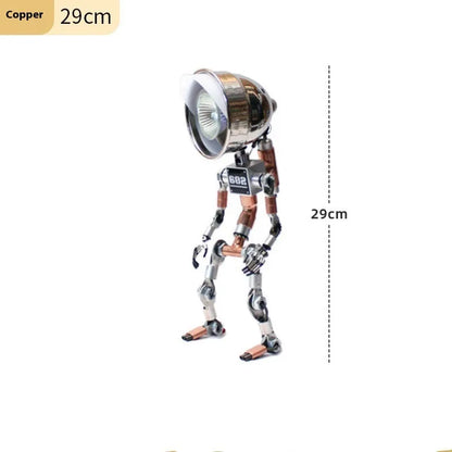 Copper robot-shaped desk lamp with custom graphic on a wooden desk next to a book.