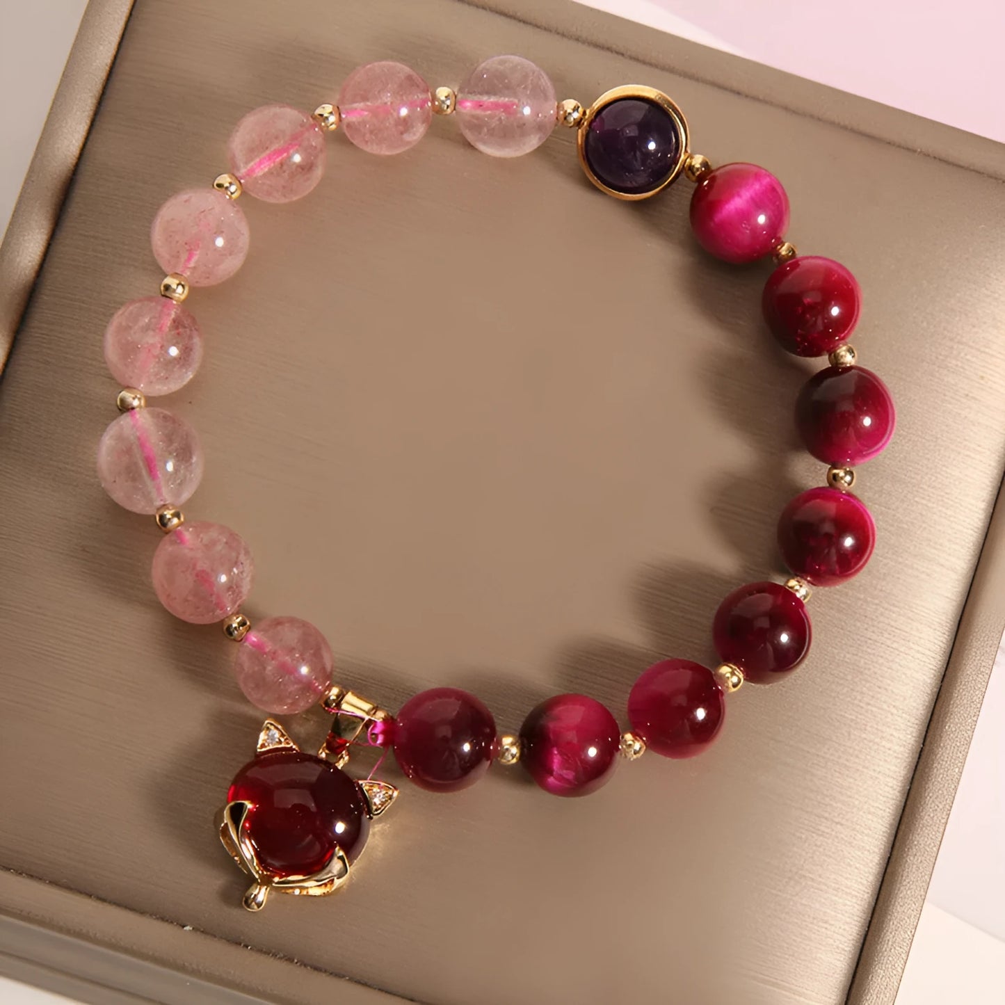 Simple women's bracelet with a red strawberry crystal charm on a black elastic rope.