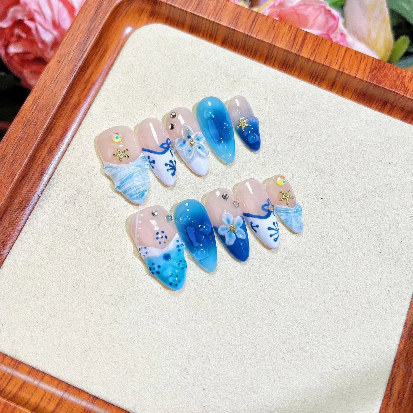 Set of 24 blue hand-painted false nails with carved floral design on transparent base, showing XS, S, M, L sizes.