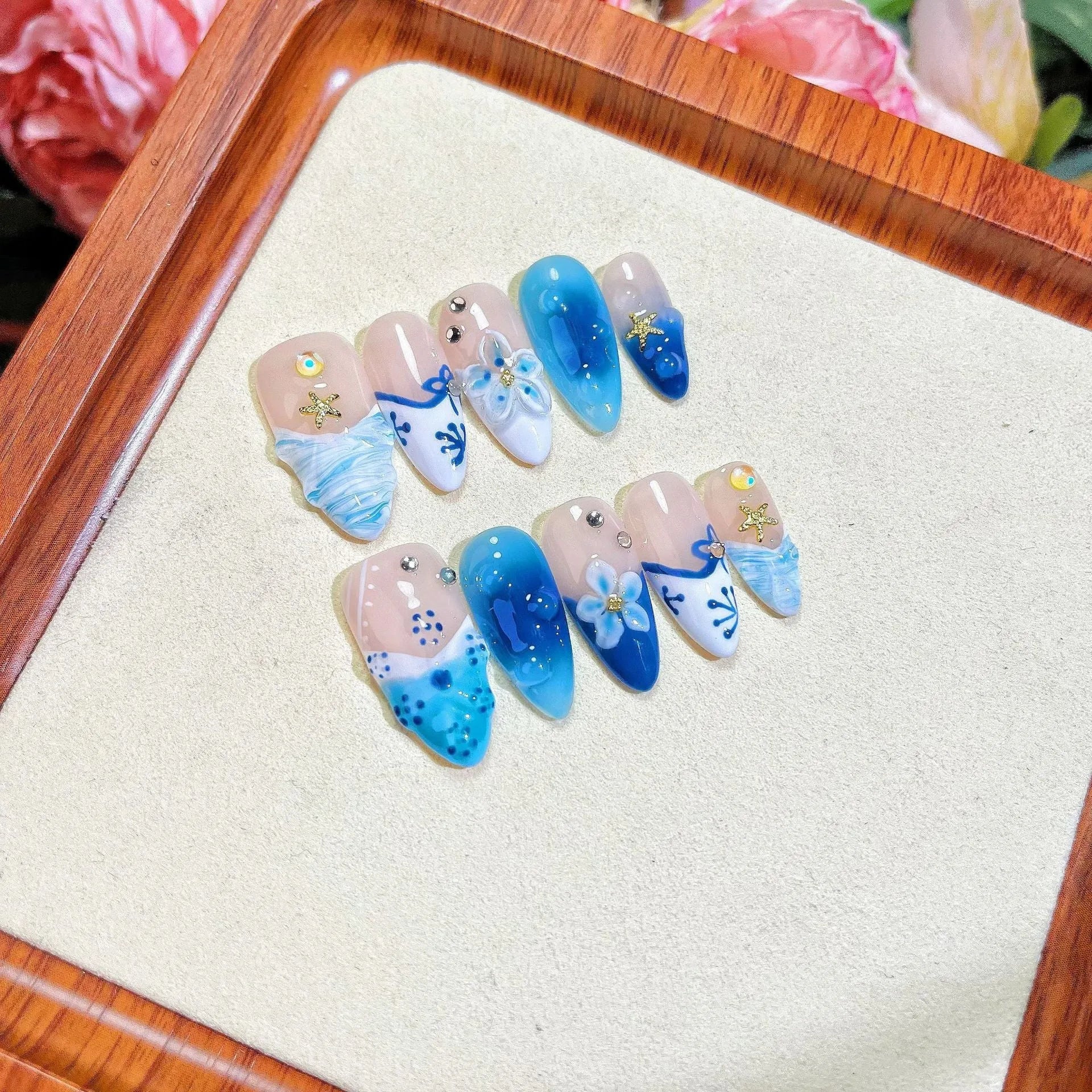 Set of 24 blue hand-painted false nails with carved floral design on transparent base, showing XS, S, M, L sizes.