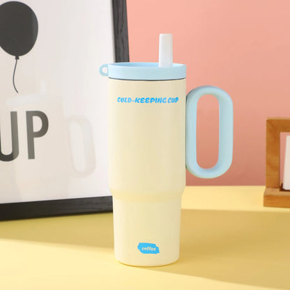 Large pink insulated straw cup with a black handle and push-button lid on a wooden table