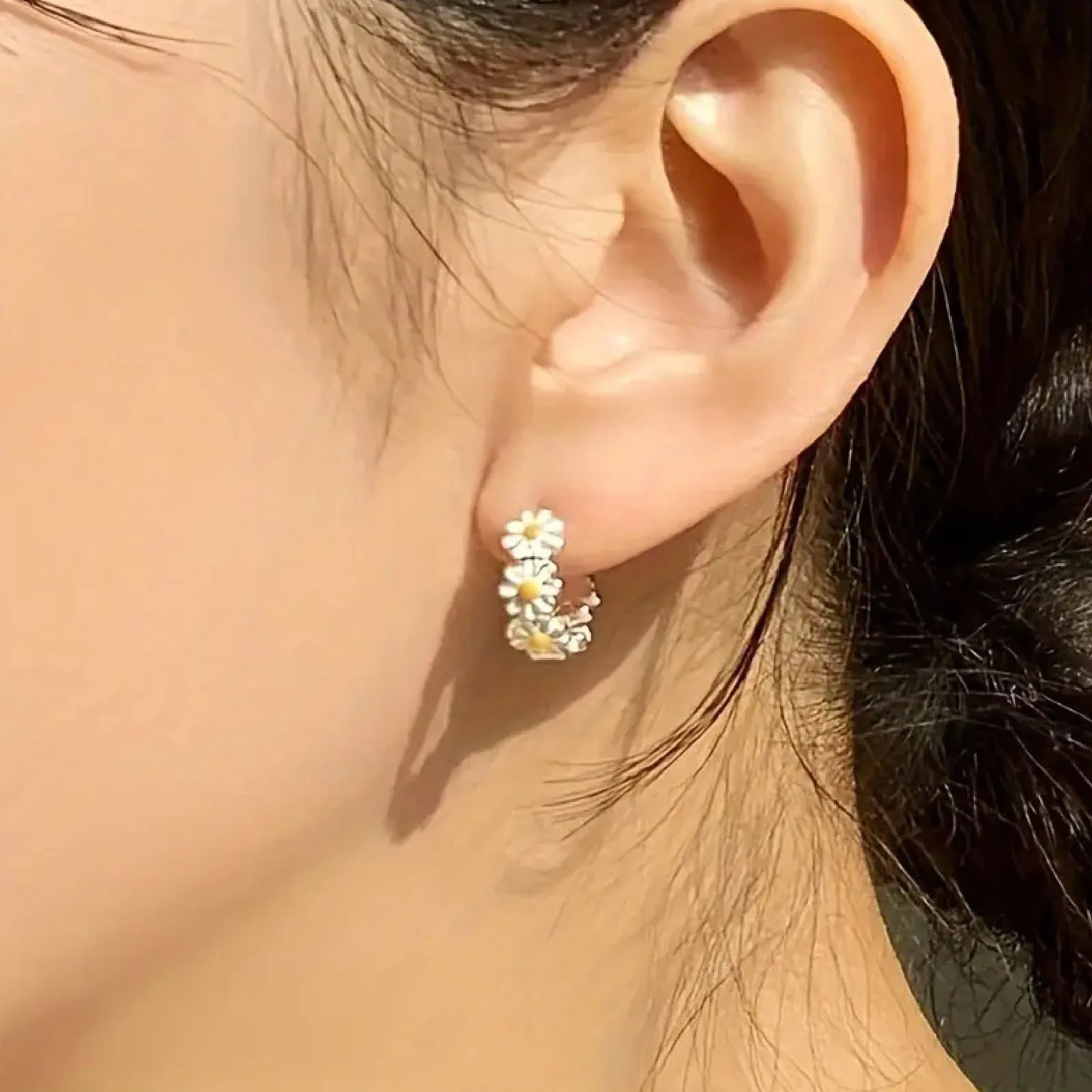 A pair of white daisy flower ring earrings with an inlaid gemstone in a platinum setting.