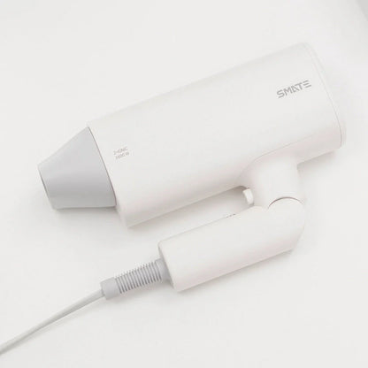 Compact, portable hair dryer with foldable handle and multiple styling settings for on-the-go hair care.
