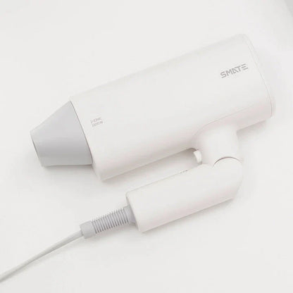 Compact, portable hair dryer with foldable handle and multiple styling settings for on-the-go hair care.