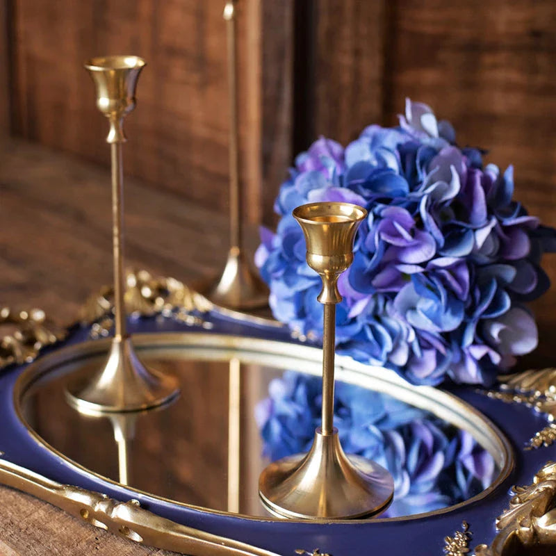 A set of three elegant brass gold candlestick holders on a wooden surface, creating a warm and inviting ambiance.
