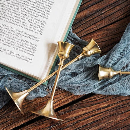 A set of three elegant brass gold candlestick holders on a wooden surface, creating a warm and inviting ambiance.