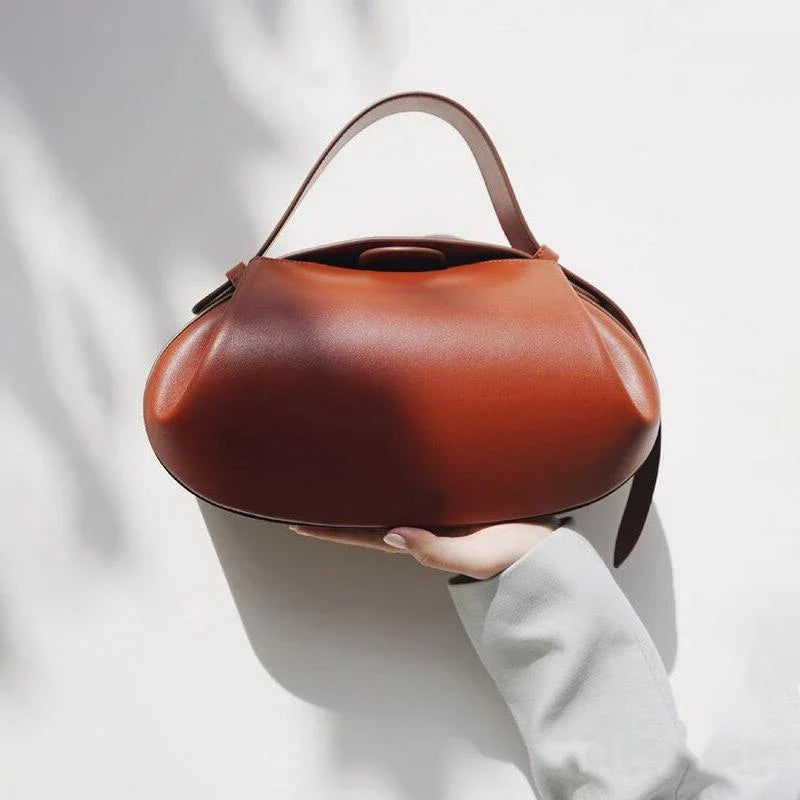 Circular vegan leather handbag in a tan color, with a sturdy build and thoughtful interior design for versatile use.