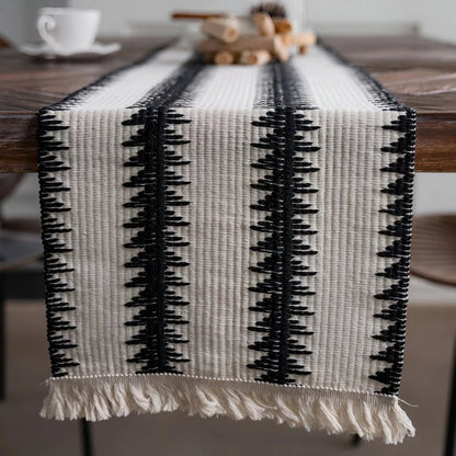 Elegant black and white cotton table runner with striped pattern and tassels, perfect for sophisticated dining experiences