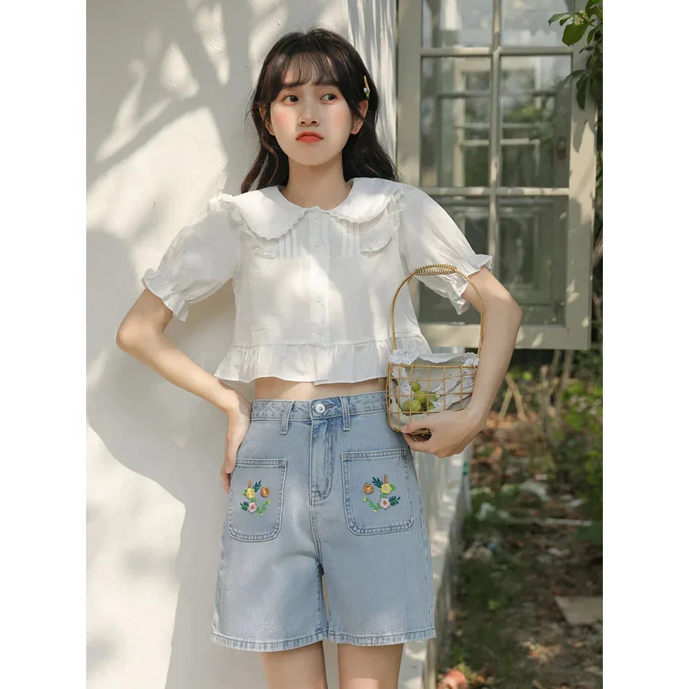 Light blue denim shorts with delicate floral embroidery, providing a stylish and comfortable summer look for women.