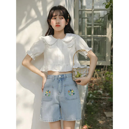 Light blue denim shorts with delicate floral embroidery, providing a stylish and comfortable summer look for women.