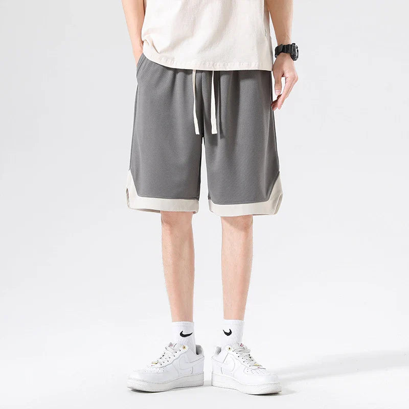 Men's loose and comfortable sports pirate shorts in white, gray, and black colors with elasticized waistband and relaxed fit