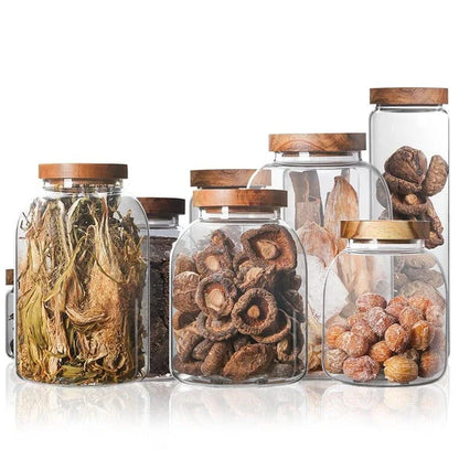 Airtight glass food storage jars with wooden lids in various sizes, perfect for organizing and preserving dry goods, spices, and pantry items in the kitchen.
