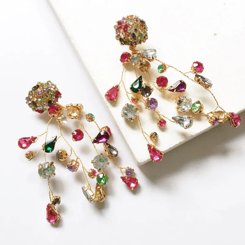 Closeup of a pair of colorful diamond and crystal earrings with a vibrant, retro-inspired design