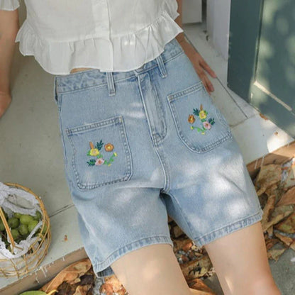 Light blue denim shorts with delicate floral embroidery, providing a stylish and comfortable summer look for women.