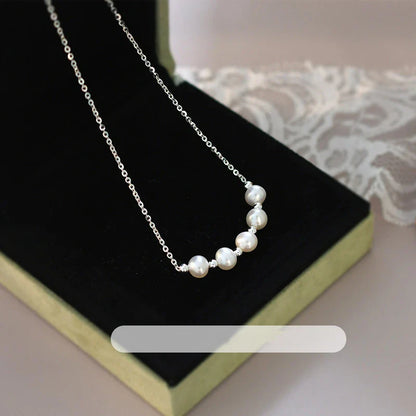 A close-up shot of a natural freshwater pearl necklace with a silver chain in a stylish multi-chain design.