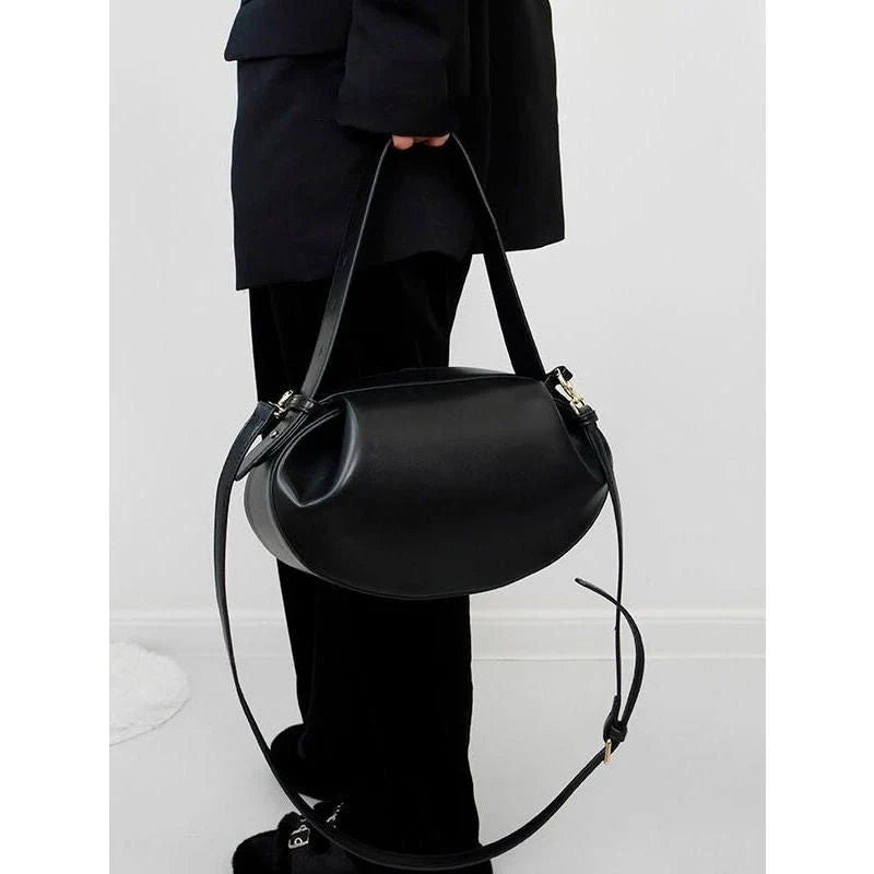 Circular vegan leather handbag in a tan color, with a sturdy build and thoughtful interior design for versatile use.