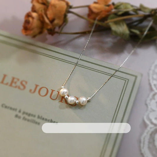 A close-up shot of a natural freshwater pearl necklace with a silver chain in a stylish multi-chain design.