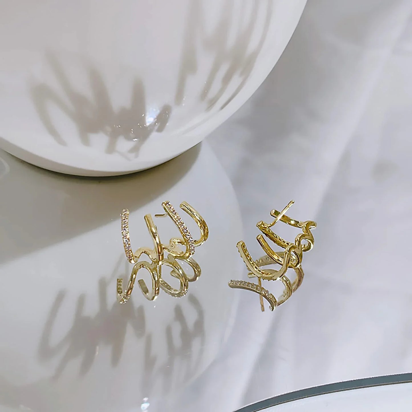 Elegant gold-toned zircon four-claw stud earrings with a classic cuff design, offering a sparkling and sophisticated look.