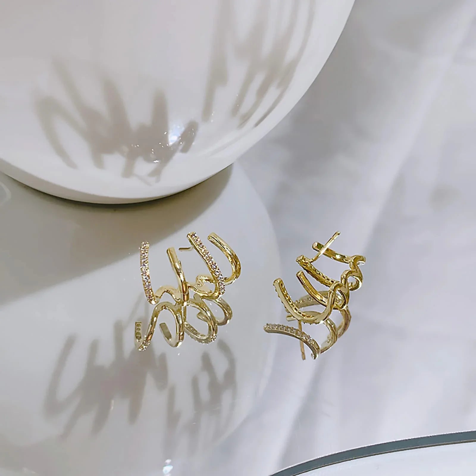 Elegant gold-toned zircon four-claw stud earrings with a classic cuff design, offering a sparkling and sophisticated look.