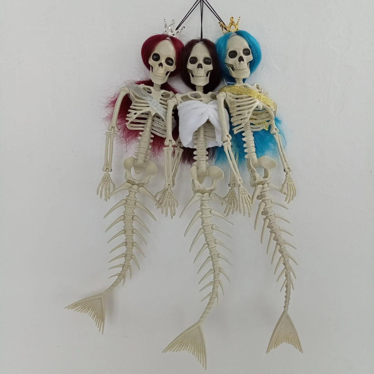 Mermaid bone pendant in various colors, including brown, dark purple, burgundy, and lake blue, hanging outdoors for Halloween decoration