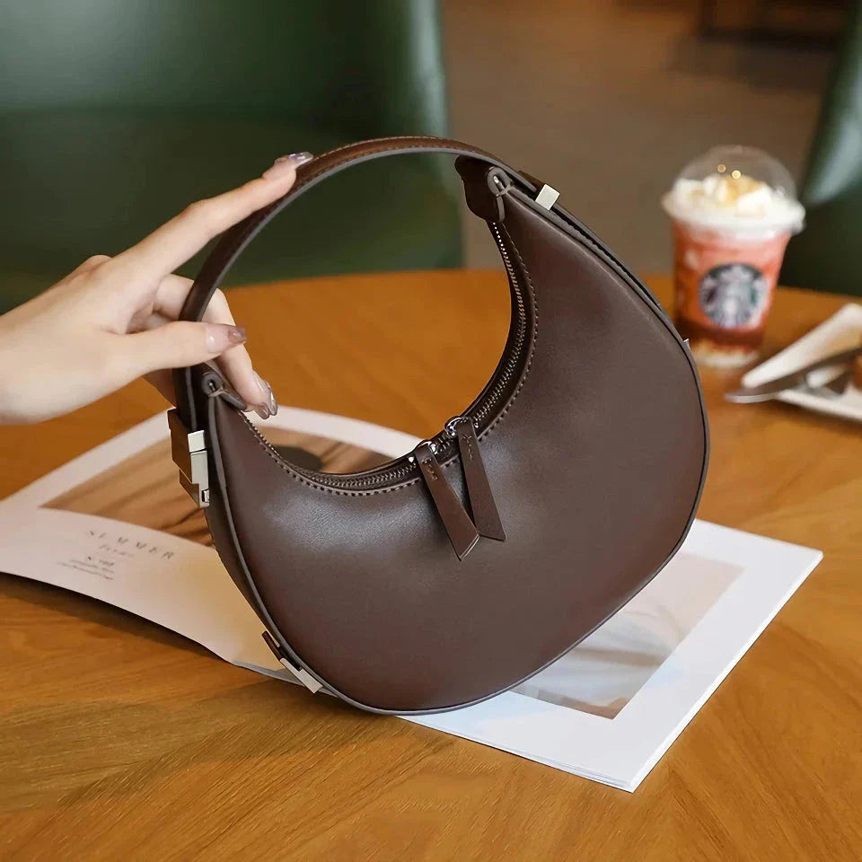 Elegant leather shoulder bag in a half-moon shape, featuring a sleek polyester lining and organized interior pockets for modern women's fashion.
