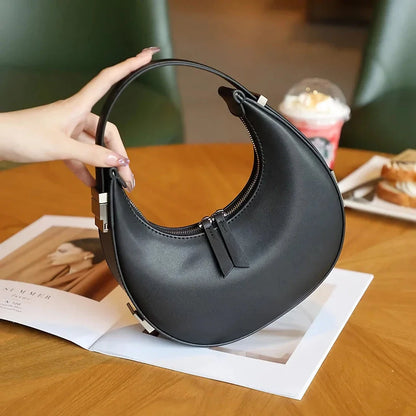 Elegant leather shoulder bag in a half-moon shape, featuring a sleek polyester lining and organized interior pockets for modern women's fashion.