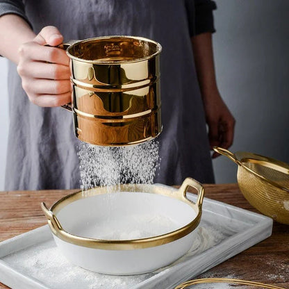 A gold baking tool set including a whisk, scraper, and flour cup made of high-quality stainless steel for versatile and elegant baking needs.