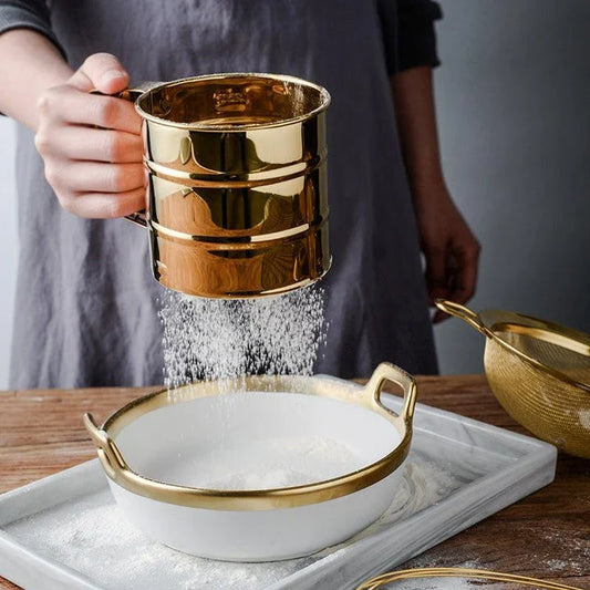 A gold baking tool set including a whisk, scraper, and flour cup made of high-quality stainless steel for versatile and elegant baking needs.