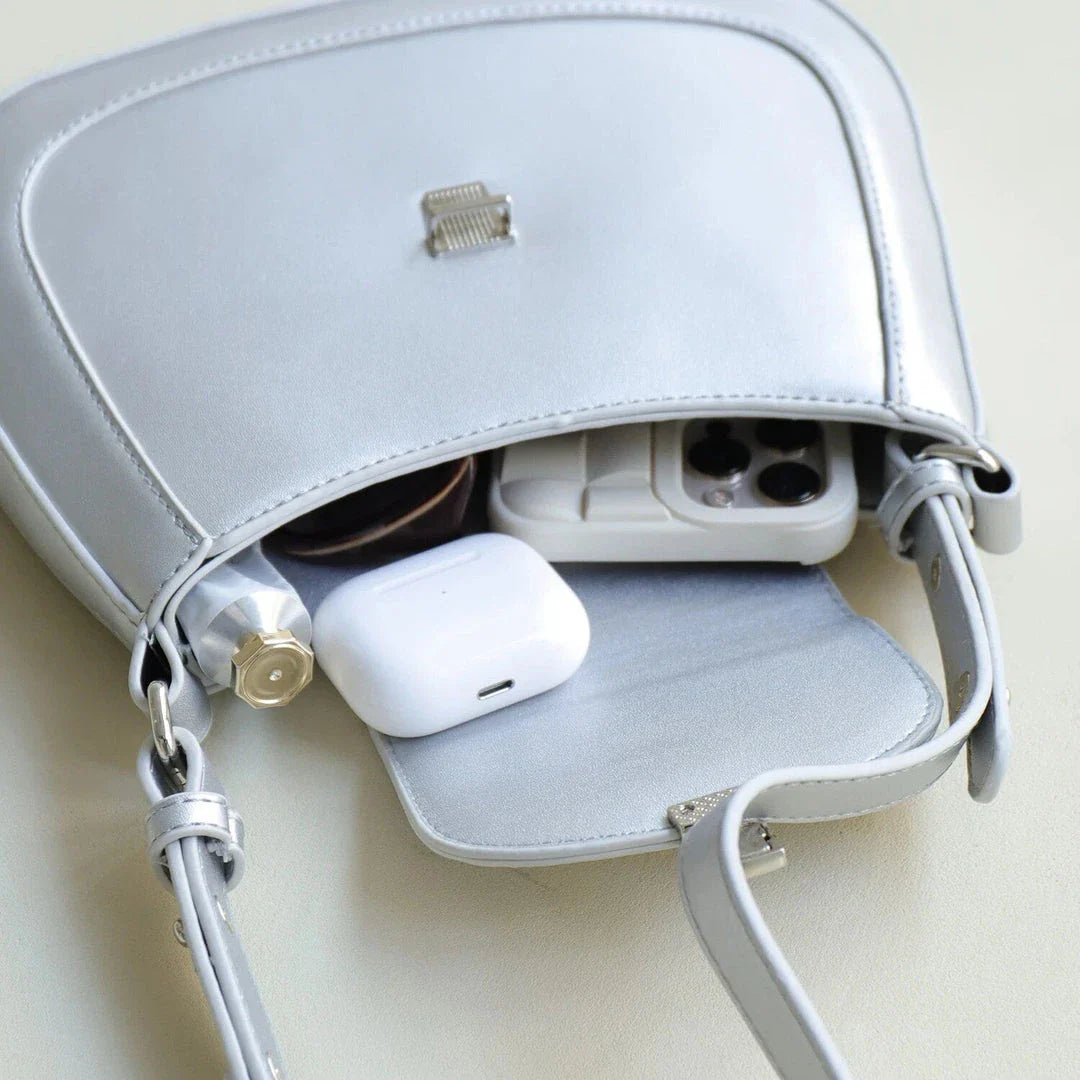 Elegant vegan leather shoulder bag with unique saddle shape, adjustable strap, and secure press lock closure