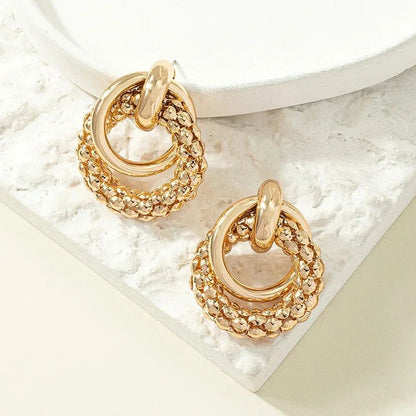 Elegant gold-toned twist dangle earrings with an intricate geometric design, perfect for adding a touch of sophistication to any outfit.