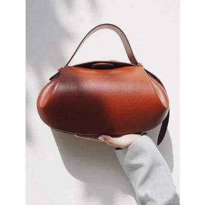 Circular vegan leather handbag in a tan color, with a sturdy build and thoughtful interior design for versatile use.