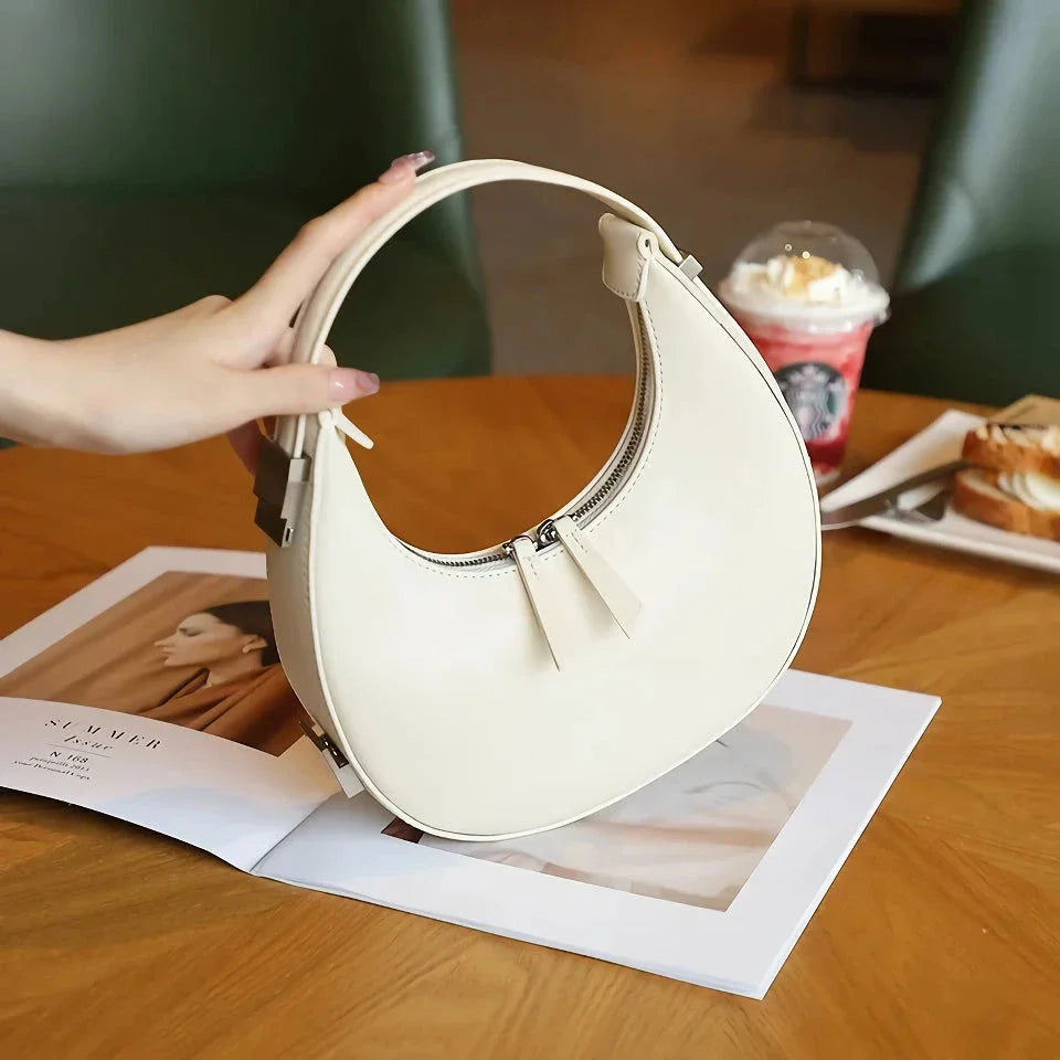 Elegant leather shoulder bag in a half-moon shape, featuring a sleek polyester lining and organized interior pockets for modern women's fashion.