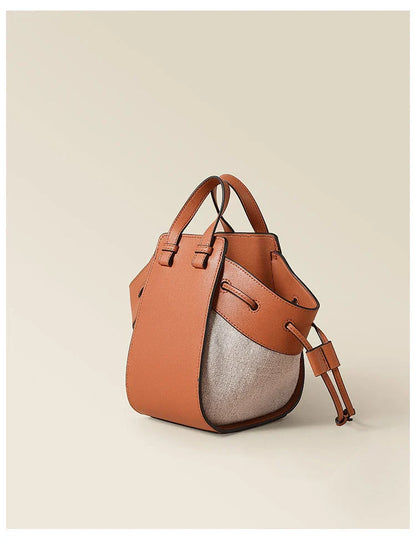 A stylish drawstring bucket bag made from premium cowhide leather and canvas, featuring a spacious main compartment, adjustable shoulder strap, and a softly structured design.