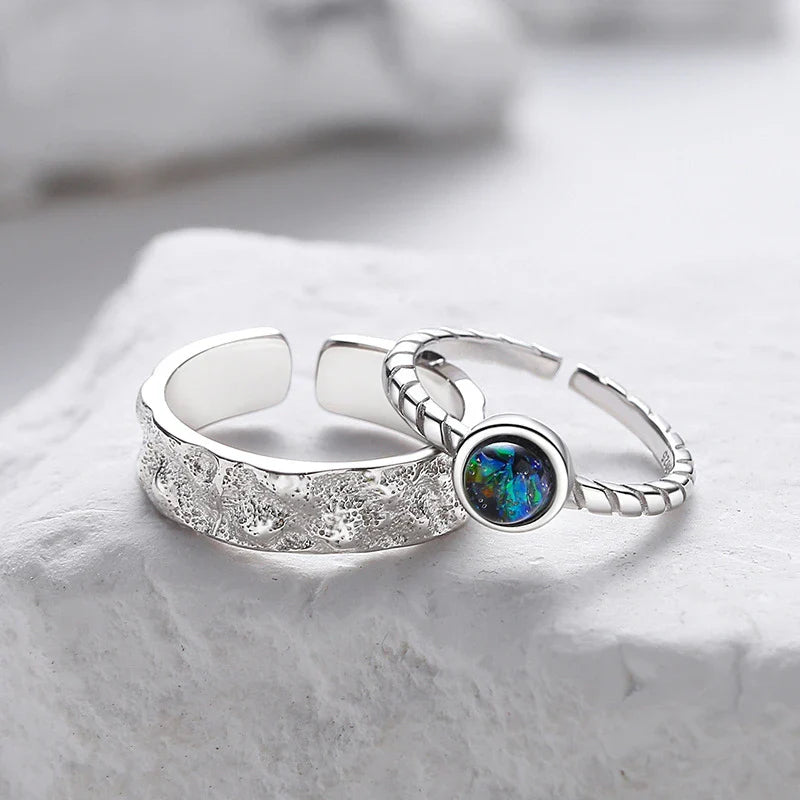 A sterling silver couple's ring set featuring a captivating glass design and an adjustable fit