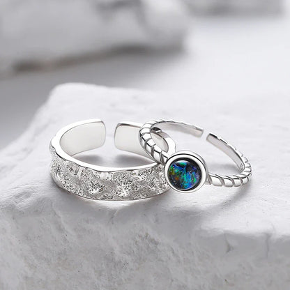 A sterling silver couple's ring set featuring a captivating glass design and an adjustable fit
