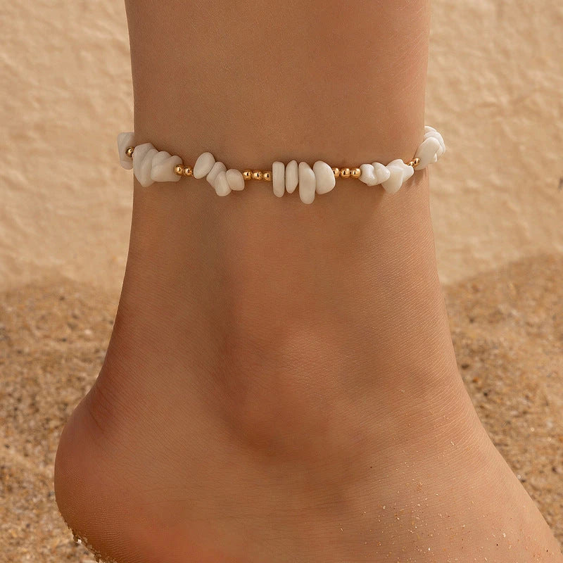 A pair of boho-inspired anklets adorned with natural shells and crushed stones, showcasing a unique geometric design for effortless summer style.
