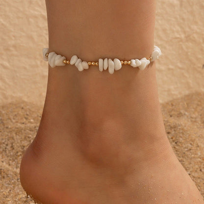 A pair of boho-inspired anklets adorned with natural shells and crushed stones, showcasing a unique geometric design for effortless summer style.