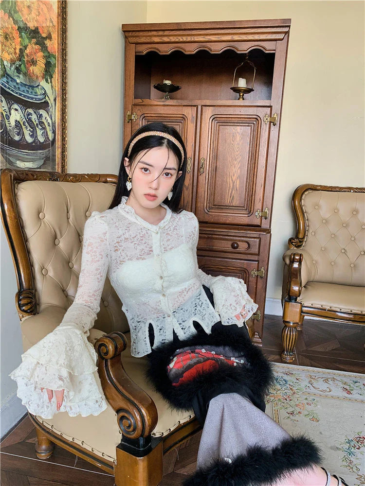 Elegant lace patchwork blouse with ruffled long sleeves and a button-down front in a classic off-white and black color palette.