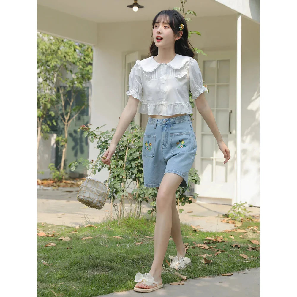 Light blue denim shorts with delicate floral embroidery, providing a stylish and comfortable summer look for women.