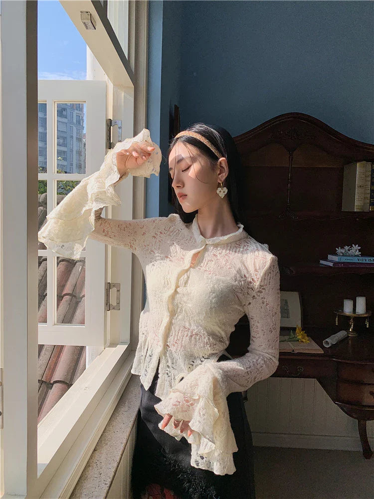 Elegant lace patchwork blouse with ruffled long sleeves and a button-down front in a classic off-white and black color palette.