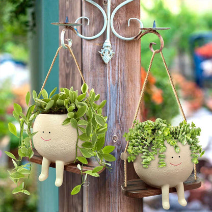 A charming face-shaped hanging planter with a swing design, perfect for adding personality and greenery to any indoor or outdoor space.