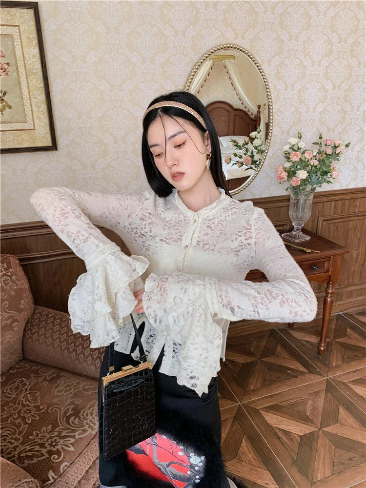 Elegant lace patchwork blouse with ruffled long sleeves and a button-down front in a classic off-white and black color palette.
